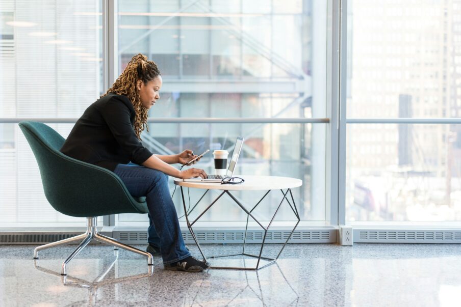 Frau sitzt an einem Tisch mit Laptop